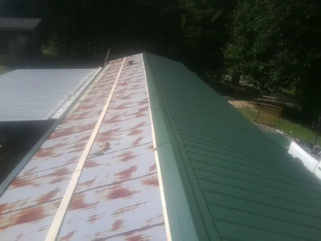 Old rusted panels beside newly installed green metal roofing — Wind Damage Roof Repair by Roofing Brothers in Belmar