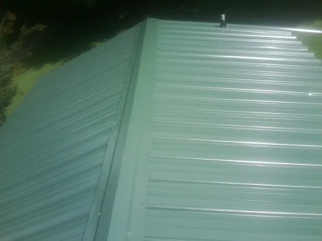 New green metal panels meeting at the ridge of a roof — Flat Roof Repair work by our crew in Belmar
