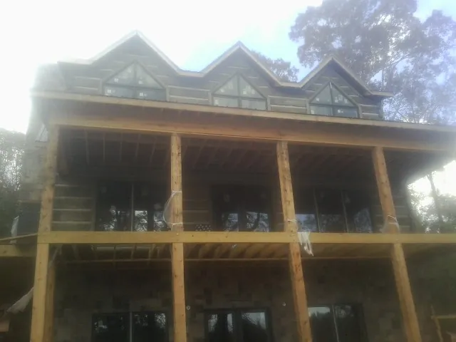 Dormers and porch framing on a large log home under construction — Roof Coating work by our crew in Belmar