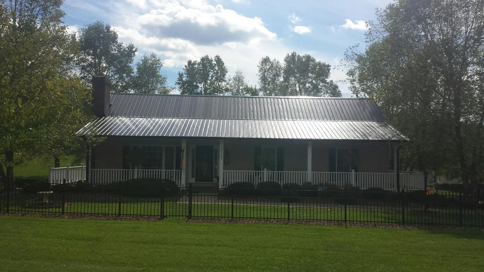 Gray metal roof on a brick ranch with a full width front porch — Gutter Guard Installation work by our crew in Belmar