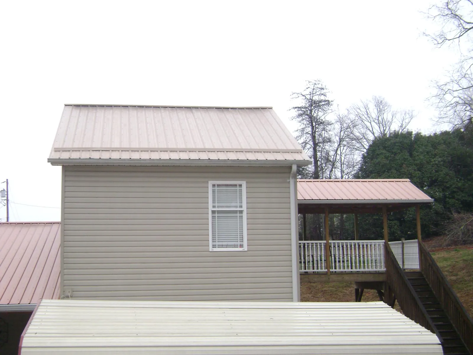 Tan metal roofs on a two story addition and attached porch, from a Roof Replacement job in Belmar