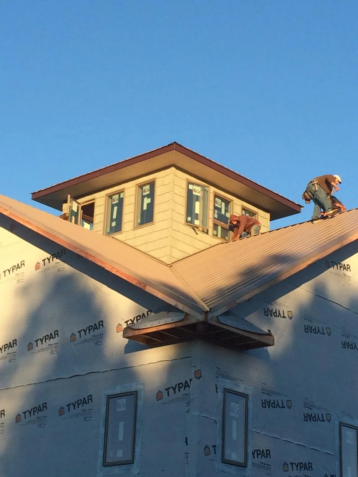Roofers working around a rooftop cupola on a new metal roof at sunset — Roof Waterproofing in Belmar by Roofing Brothers